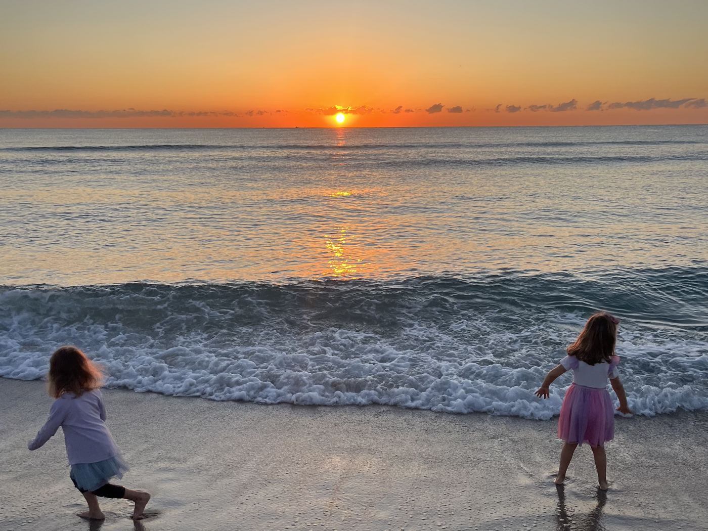 Melanie's two daughters running into the waves at sunset