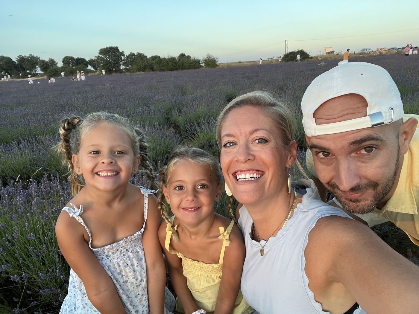 Melanie, her husband and their two daughters smiling in a lavender field at sunset