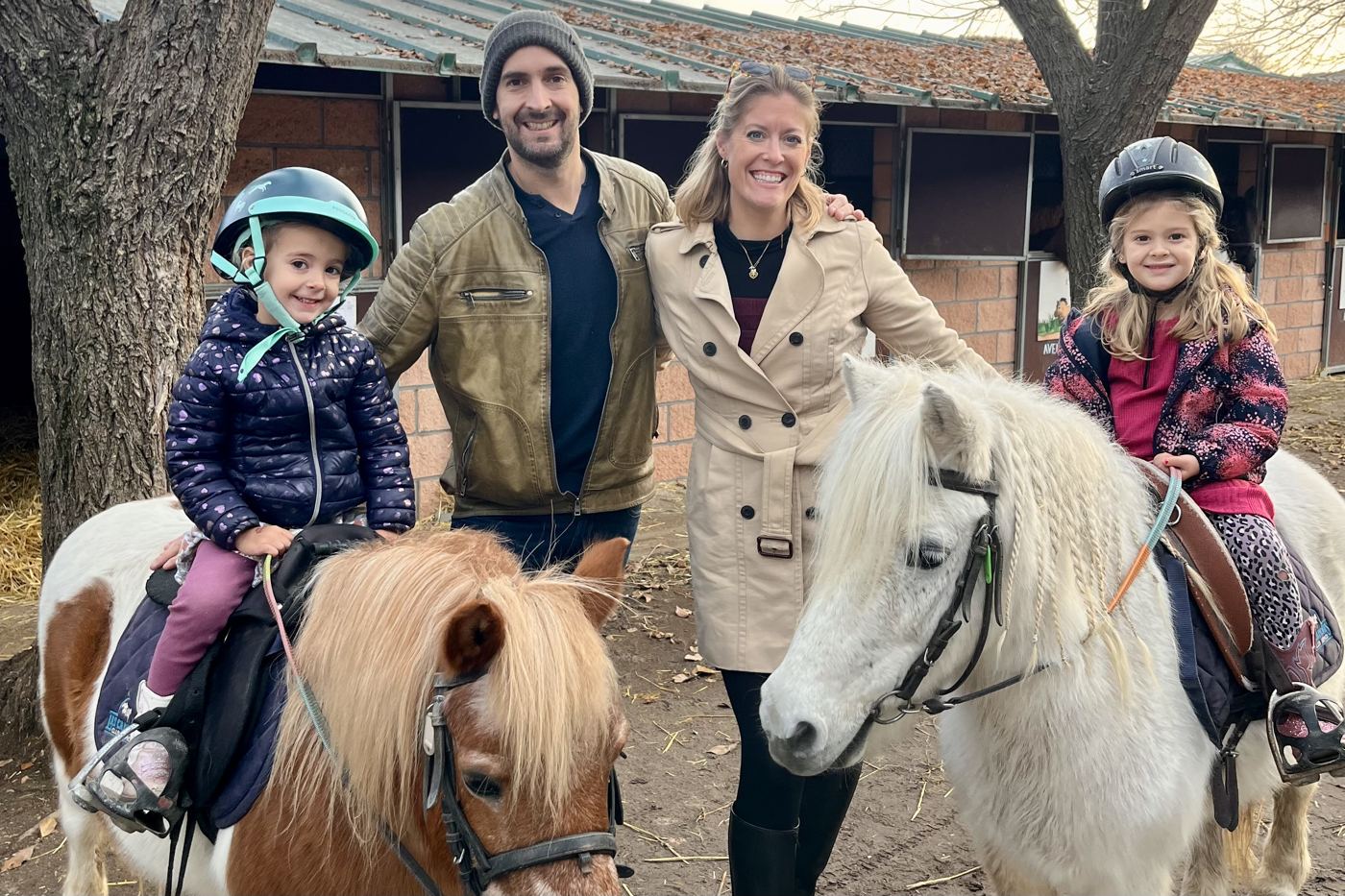 Melanie and her husband with their daughters riding ponies