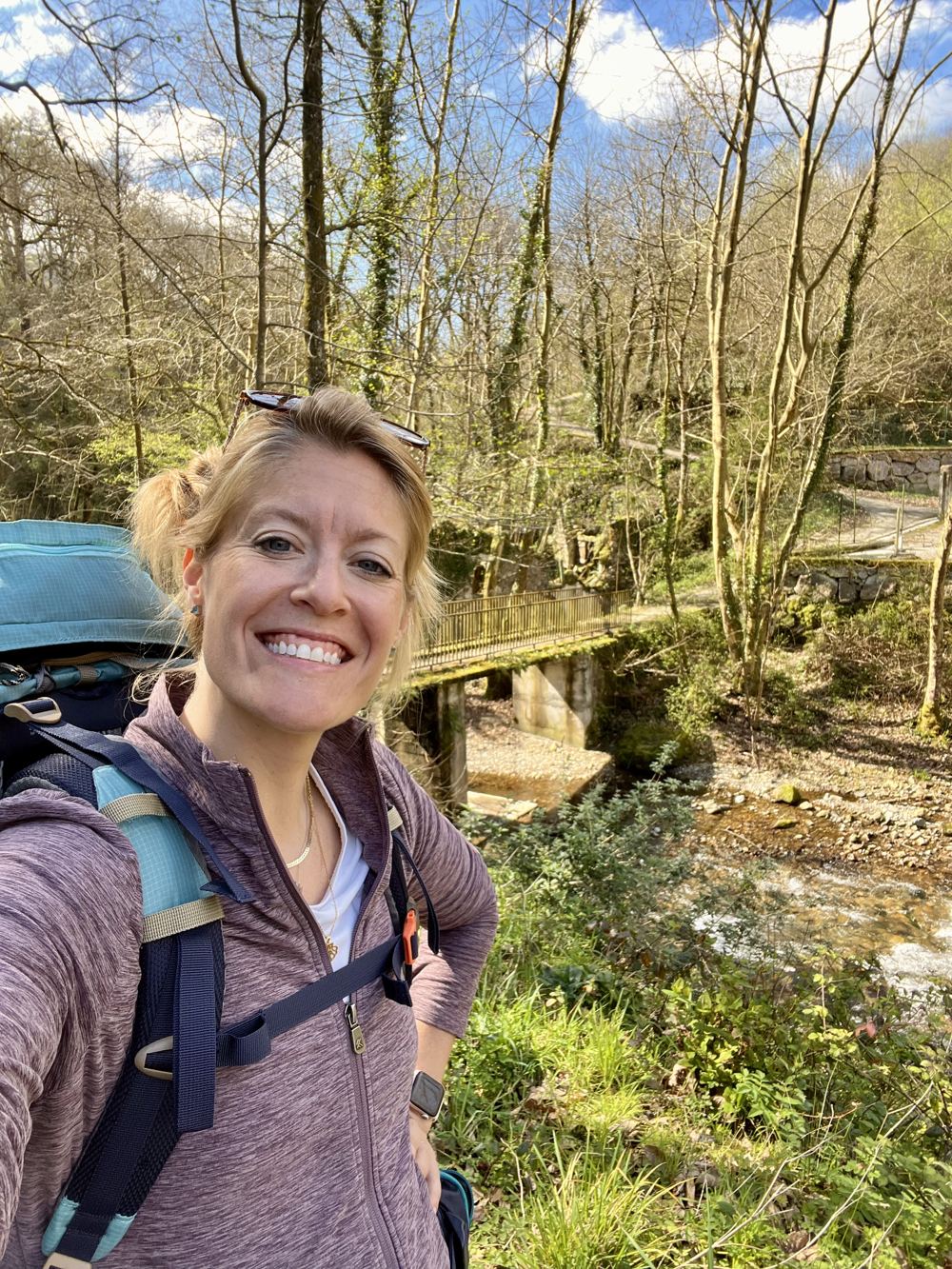 Melanie Wood smiling on a forest hike with her backpack on
